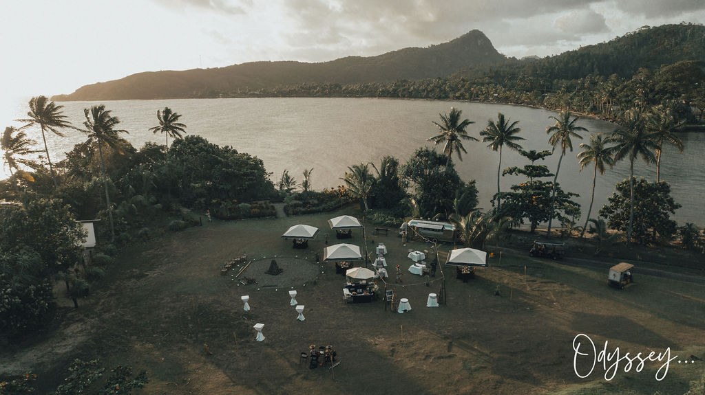 A private event set among the palms at dusk, marquees and tables from the air