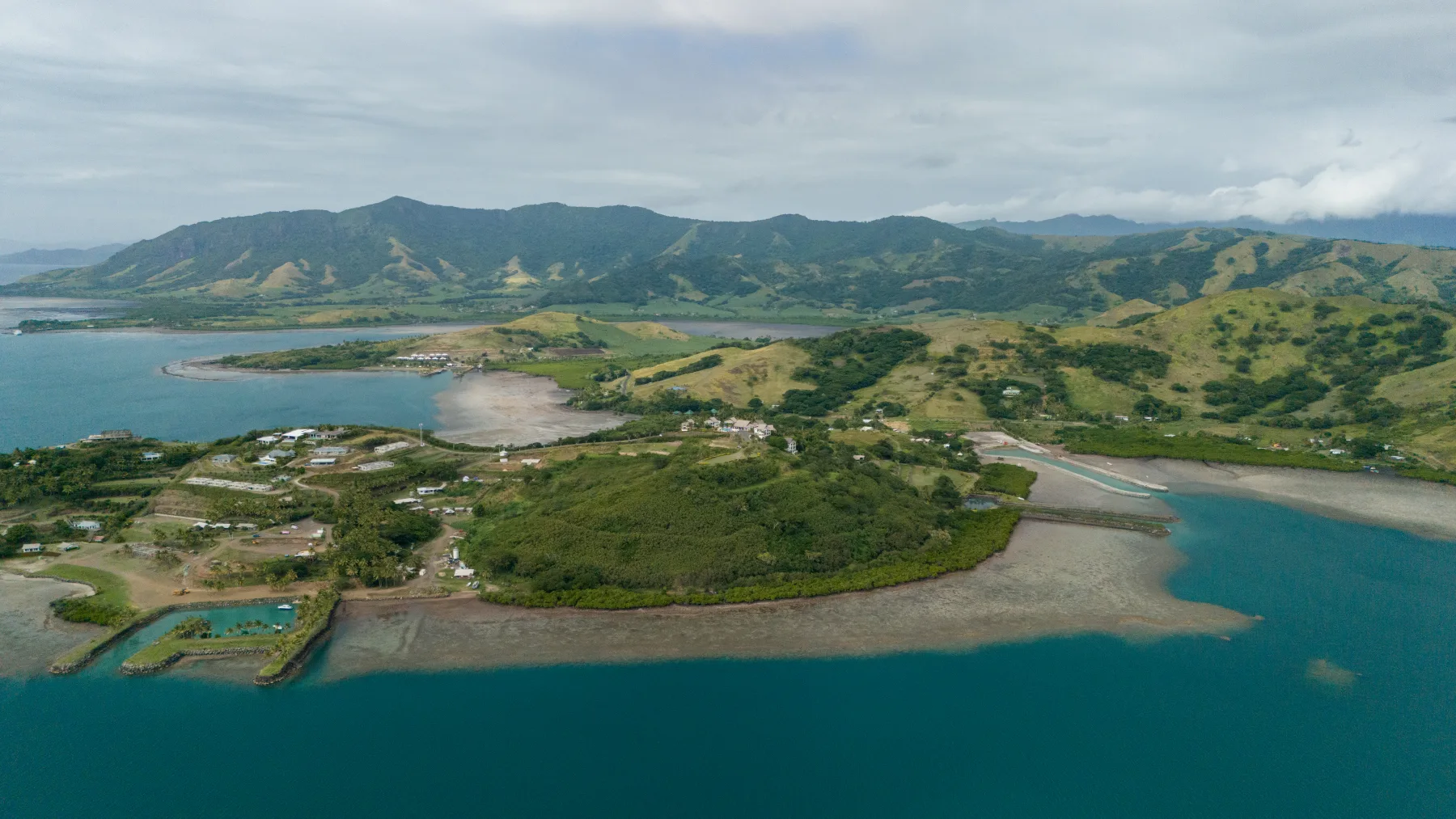 A wide aerial view of Fiji's coast, river flats and green highlands