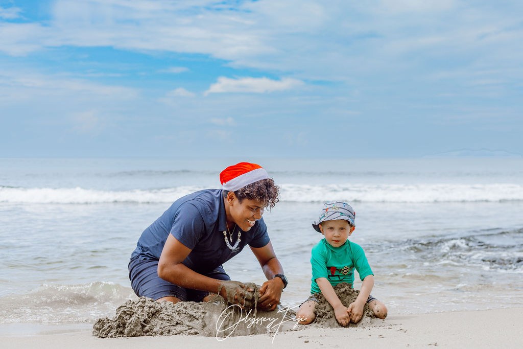 An Odyssey guide building a sandcastle with a young guest on the beach