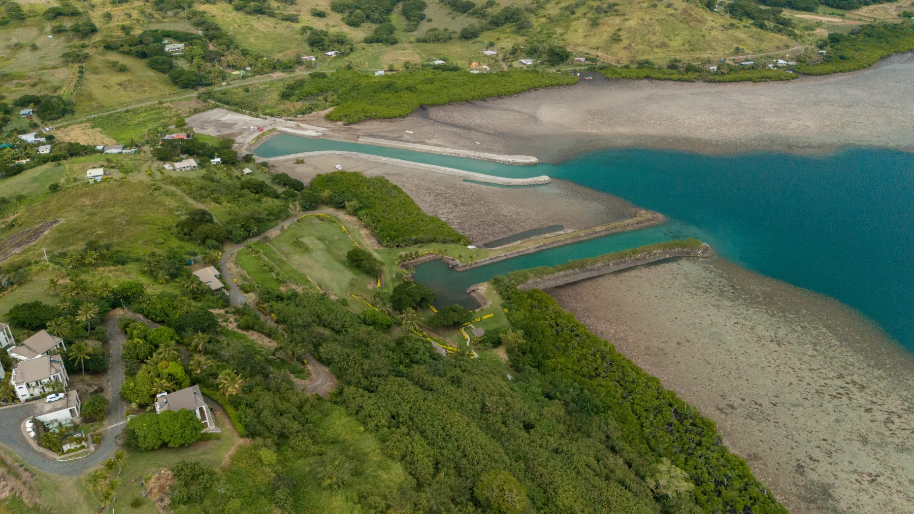 A tidal channel cutting through reef flats beside a green coast